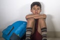 Young sad scared latin kid 8 years old in school uniform and backpack sitting alone crying depressed and frightened suffering abus Royalty Free Stock Photo