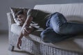 Lifestyle dramatic light portrait of young sad and depressed man lying at shady home couch in pain and depression feeling lost loo Royalty Free Stock Photo