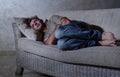 Lifestyle dramatic light portrait of young sad and depressed man lying at shady home couch in pain and depression feeling lost loo Royalty Free Stock Photo