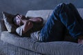 Lifestyle dramatic light portrait of young sad and depressed man lying at shady home couch in pain and depression feeling stressed Royalty Free Stock Photo