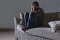 Lifestyle dramatic light portrait of young sad and depressed man sitting at shady home couch in pain and depression feeling stress Royalty Free Stock Photo