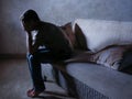 Lifestyle dramatic light portrait of young sad and depressed man sitting at shady home couch in pain and depression feeling stress Royalty Free Stock Photo