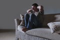 Lifestyle dramatic light portrait of young sad and depressed man sitting at shady home couch in pain and depression feeling stress Royalty Free Stock Photo