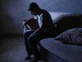Lifestyle dramatic light portrait of young sad and depressed man sitting at shady home couch in pain and depression feeling stress Royalty Free Stock Photo