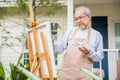 Lifestyle elderly people smile paint at his easel outside home