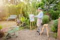 Lifestyle elderly people smile paint at his easel outside home