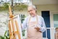 Lifestyle elderly people smile paint at his easel outside home