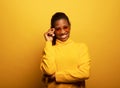 Portarit of young beautiful african-american young woman smiling broadly over yellow background