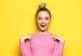 Lifestyle, emotion and people concept: Young surprised woman wearing pink shirt over yellow background