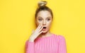 Lifestyle, emotion and people concept: Young surprised woman wearing pink shirt over yellow background