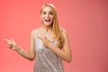 Excited carefree happy young attractive woman joyful attend awesome party in silver beautiful glittering dress pointing Royalty Free Stock Photo