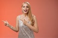 Excited carefree happy young attractive woman joyful attend awesome party in silver beautiful glittering dress pointing Royalty Free Stock Photo