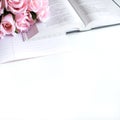 Flat lay with different accessories; flower bouquet, pink roses, open book, Bible