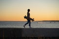 Lifestyle and freedom: young girl with skateboard walk at sunset. Silhouette of trendy female skater Royalty Free Stock Photo