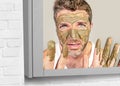 Lifestyle funny portrait of young attractive and surprised man horrified looking himself on bathroom mirror ugly and weird face ap Royalty Free Stock Photo