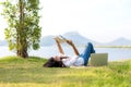 Lifestyle Girl enjoy listening music and reading a book and play laptop on the grass field of the nature park in the morning gree