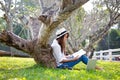 Lifestyle Girl enjoy listening music and reading a book and play laptop on the grass field of the nature park in the morning gree Royalty Free Stock Photo