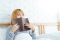 Lifestyle happy young Asian woman enjoying lying on the bed reading book pleasure in casual clothing at home. Royalty Free Stock Photo