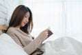 Lifestyle happy young Asian woman enjoying lying on the bed reading book pleasure in casual clothing at home. Royalty Free Stock Photo