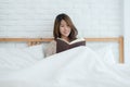 Lifestyle happy young Asian woman enjoying lying on the bed reading book pleasure in casual clothing at home. Royalty Free Stock Photo