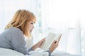 Lifestyle happy young Asian woman enjoying lying on the bed reading book pleasure in casual clothing at home. Royalty Free Stock Photo