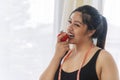 Lifestyle or Health care or weight loss concept. Happy fat young woman with measure tape eating organic fresh red tomato in own Royalty Free Stock Photo