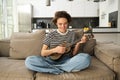 Lifestyle and hobbies concept. Young smiling woman on sofa, playing ukulele, singing and learning strumming pattern for