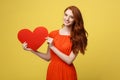 Lifestyle and Holiday Concept - Portrait Young happy red hair woman in orange beautiful dress holding big red heart Royalty Free Stock Photo