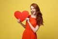 Lifestyle and Holiday Concept - Portrait Young happy red hair woman in orange beautiful dress holding big red heart Royalty Free Stock Photo
