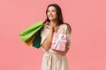 Lifestyle, holidays and emotions concept. Cheerful carefree young feminine woman holding shopping bags and wrapped cute Royalty Free Stock Photo