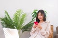 Lifestyle at home concept, Asian woman sitting on chair and use smartphone to surfing social media Royalty Free Stock Photo