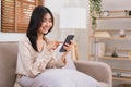 Lifestyle at home concept, Asian woman use smartphone to surfing social media while sitting on sofa Royalty Free Stock Photo