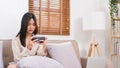 Lifestyle at home concept, Young Asian woman use smartphone to playing games while sitting on sofa Royalty Free Stock Photo