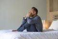 Young attractive overwhelmed and depressed man sitting on bed worried and frustrated suffering depression crisis covering face Royalty Free Stock Photo