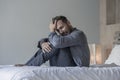 Young attractive overwhelmed and depressed man sitting on bed worried and frustrated suffering depression crisis covering face Royalty Free Stock Photo