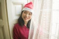 Lifestyle home portrait of young beautiful and happy Asian Korean woman in Santa Claus hat and red jersey enjoying Christmas time Royalty Free Stock Photo