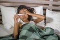 Lifestyle home portrait of young beautiful and sweet 8 years old female child holding thermometer lying sick on bed having flu or