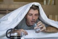 Lifestyle home portrait of young exhausted and wasted man waking up suffering headache and hangover after drinking alcohol at nigh