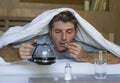 Lifestyle home portrait of young exhausted and wasted man waking up suffering headache and hangover after drinking alcohol at nigh