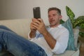 Lifestyle home portrait of young handsome and happy man using mobile phone lying relaxed and cheerful at home sofa couch using int Royalty Free Stock Photo