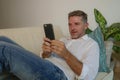 Lifestyle home portrait of young handsome and happy man using mobile phone lying relaxed and cheerful at home sofa couch using int Royalty Free Stock Photo