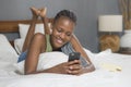 Lifestyle home portrait of young happy and attractive black African American woman lying on bed using social media app in mobile Royalty Free Stock Photo