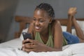 Lifestyle home portrait of young happy and attractive black African American woman lying on bed using social media app in mobile Royalty Free Stock Photo