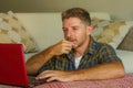 Lifestyle home portrait of young happy and attractive man at home sofa couch working on laptop computer using the internet relaxed Royalty Free Stock Photo