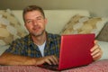 Lifestyle home portrait of young happy and attractive man at home sofa couch working on laptop computer using the internet relaxed Royalty Free Stock Photo