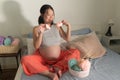 Lifestyle home portrait of young happy and beautiful Asian Chinese woman knitting shoes for the new baby relaxed in her bedroom in Royalty Free Stock Photo