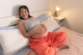 Lifestyle home portrait of young happy and beautiful Asian Korean woman pregnant sitting on bed relaxed and excited about Royalty Free Stock Photo