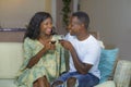 Lifestyle home portrait of young romantic and happy black African American couple in love drinking wine cup at living room couch Royalty Free Stock Photo