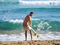 A surfer getting ready for the surf. .Man is applying wax to surfboard shortboard on vacation