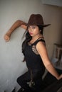 Lifestyle images of young Indian sexy girl in black western dress and cowboy hat on the landing of a staircase with railings